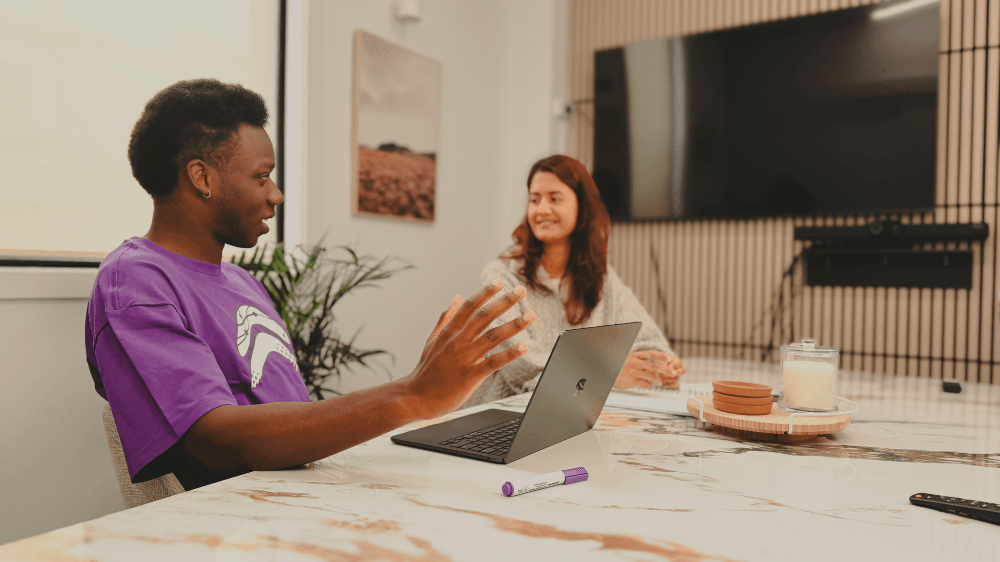 Two co-workers seated in a meeting room discussing